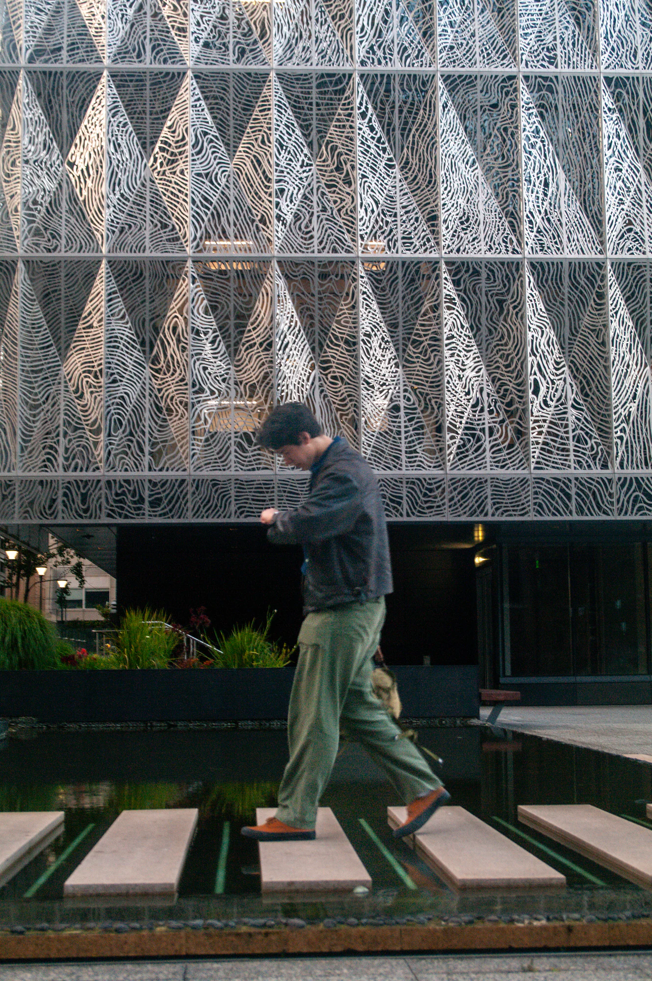 Motion-blurred pedestrian passing an intricate patterned building facade.