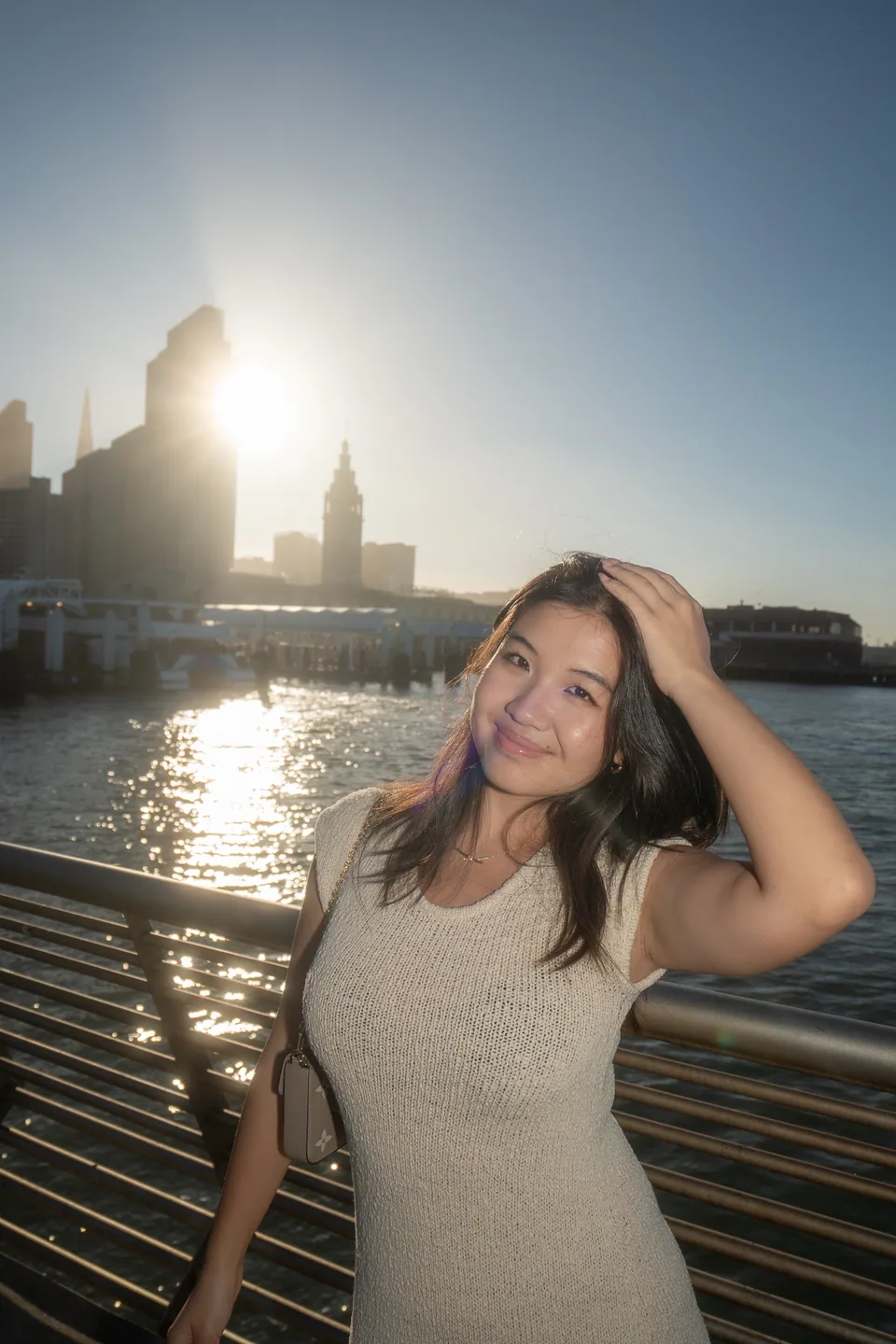 Sunlit waterfront portrait with the San Francisco skyline behind the subject.