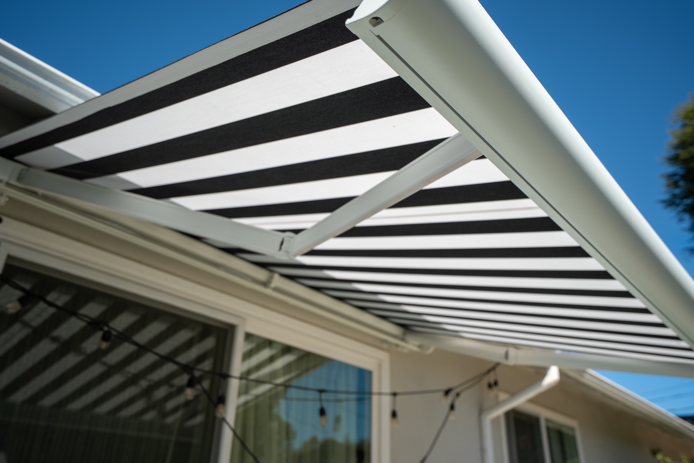 Close architectural detail of a striped retractable awning extended above a residential patio.
