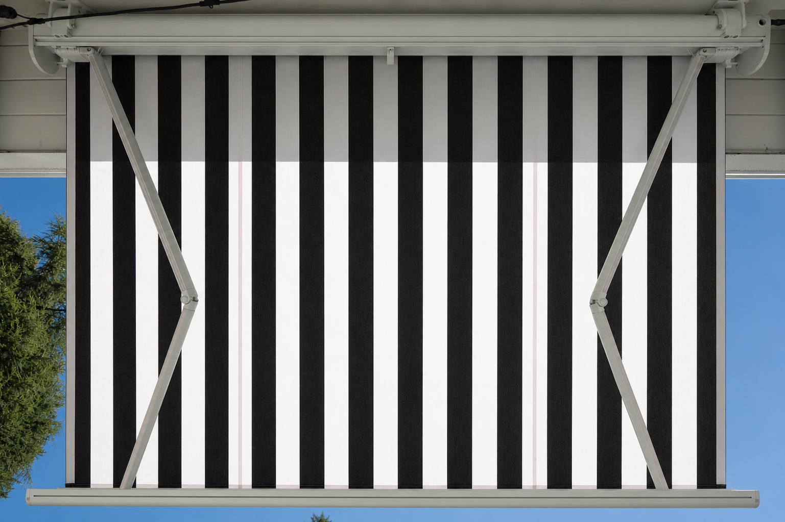 Overhead architectural view of a black-and-white striped retractable patio awning against a clear blue sky.